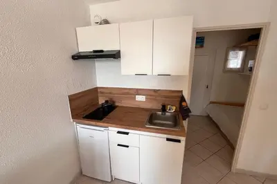 a small kitchen with a sink and white cabinets at Charming studio with sea view Gruissan in Gruissan