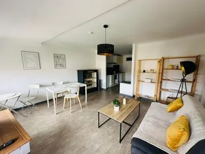 a living room with a couch and a table at Grand T2 50m2 Narbonne centre, vue sur cathédrale in Narbonne