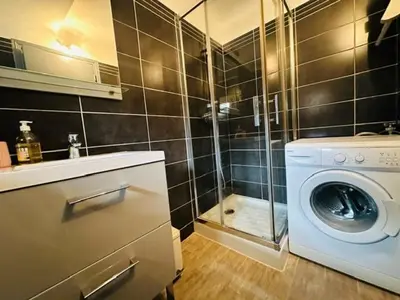 a bathroom with a washing machine and a shower at Grand T2 50m2 Narbonne centre, vue sur cathédrale in Narbonne