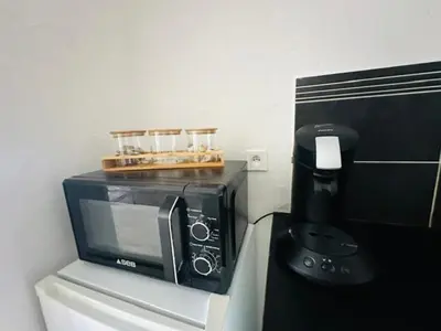 a microwave sitting on a counter next to a coffee maker at Grand T2 50m2 Narbonne centre, vue sur cathédrale in Narbonne