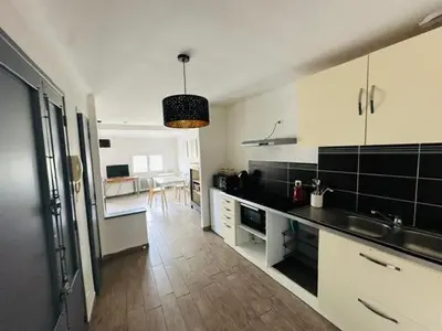 a kitchen with black and white cabinets and a table at Grand T2 50m2 Narbonne centre, vue sur cathédrale in Narbonne