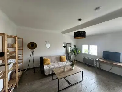 a living room with a couch and a table at Grand T2 50m2 Narbonne centre, vue sur cathédrale in Narbonne