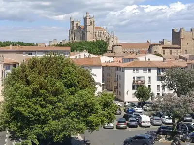 a city with cars parked in a parking lot with a cathedral at Grand T2 50m2 Narbonne centre, vue sur cathédrale in Narbonne