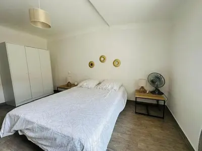 a bedroom with a white bed and two tables at Grand T2 50m2 Narbonne centre, vue sur cathédrale in Narbonne