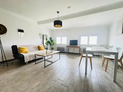 a living room with a couch and a table at Grand T2 50m2 Narbonne centre, vue sur cathédrale in Narbonne
