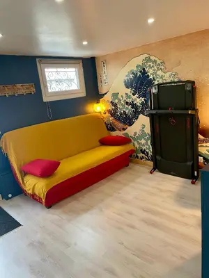 a yellow and red couch in a room with a painting at La Maison Nikaïa in Narbonne