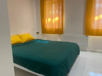 a bed with a green blanket and yellow pillows in a room at Chambre privée en centre-ville in Trèbes
