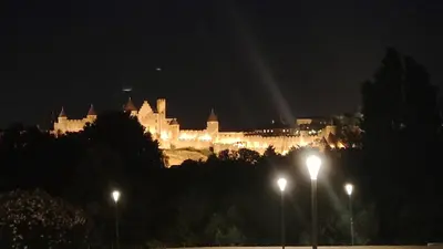 a large castle is lit up at night at Chambre privée en centre-ville in Trèbes