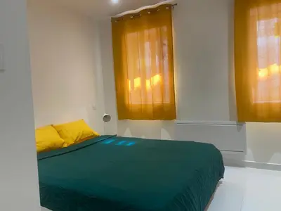 a bedroom with a green bed and two windows at Chambre privée en centre-ville in Trèbes