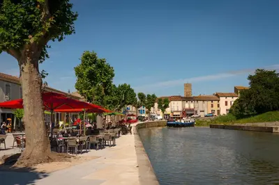 a canal with tables and chairs next to a river at Chambre privée en centre-ville in Trèbes