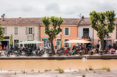a group of people sitting at tables near a river at Chambre privée en centre-ville in Trèbes