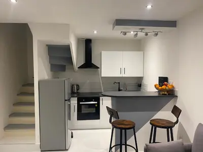 a kitchen with a counter and two bar stools at Chambre privée en centre-ville in Trèbes