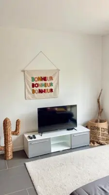 a living room with a tv on a white wall at Appartement Malibu in Lapalme