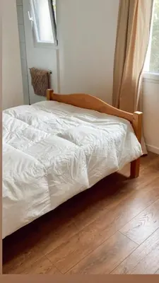 a bed with white sheets on a wooden floor at Appartement Malibu in Lapalme