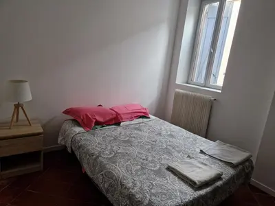 a bedroom with a bed with red pillows and a window at Chez Sylvie in Carcassonne