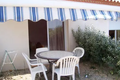 a table and chairs on a patio with a striped umbrella at Le Fenouillet Chambres D'hotes proche des Grands Buffets in Narbonne