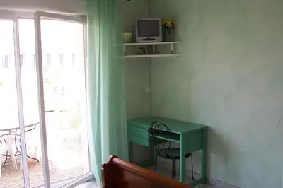 a room with a green desk with a television on a window at Le Fenouillet Chambres D'hotes proche des Grands Buffets in Narbonne