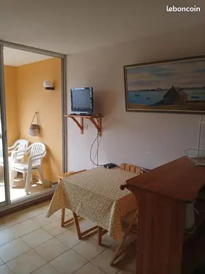 a living room with a table and a television at Location de vacances bord de mer Gruissan in Gruissan