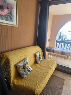 a yellow couch with two pillows in a living room at Location de vacances bord de mer Gruissan in Gruissan