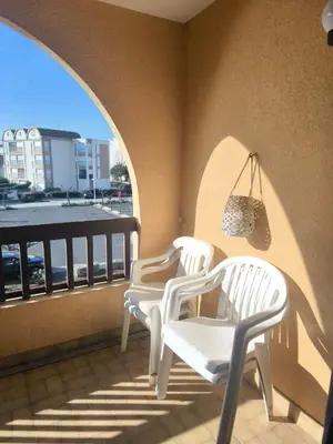 three white chairs on a balcony with a view at Location de vacances bord de mer Gruissan in Gruissan