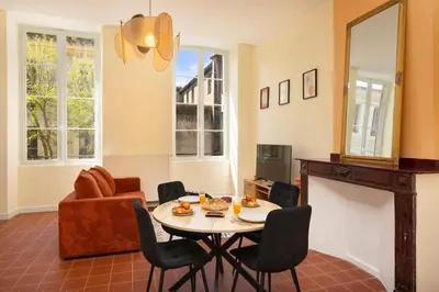 a living room with a table and chairs at L'instant Voltaire in Carcassonne