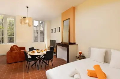 a bedroom with a bed and a table and a room at L'instant Voltaire in Carcassonne