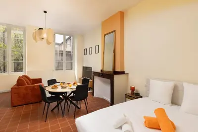 a bedroom with a bed and a table and a room at L'instant Voltaire in Carcassonne