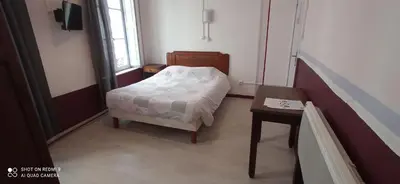 a small bedroom with a bed and a table at Hôtel de Paris - Narbonne in Narbonne