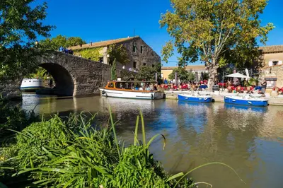 a group of boats in a river with a bridge at Maison T3 in Sallèles-dʼAude