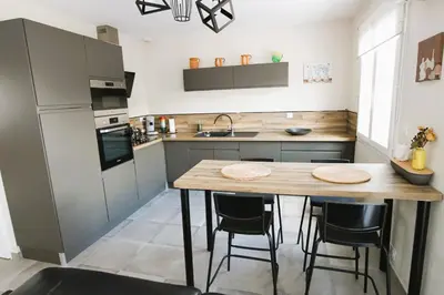 a kitchen with a wooden table and some chairs at Maison T3 in Sallèles-dʼAude