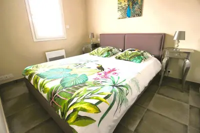 a bedroom with a bed with a tropical bedspread at Maison T3 in Sallèles-dʼAude