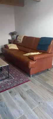 a brown leather couch sitting in a living room at Gîte familial 10 places in Castelnau-de-Brassac
