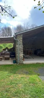 a pavilion with a stone building with a table and benches at Gîte familial 10 places in Castelnau-de-Brassac