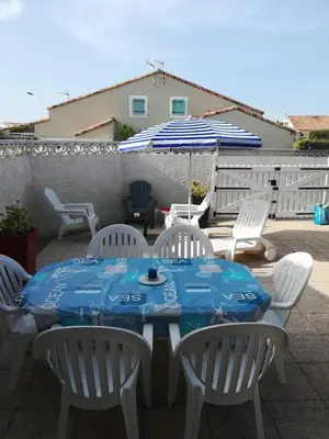 a table and chairs and an umbrella on a patio at Maison de vacances climatisée 600m de la mer Cour privative et parking in Port-la-Nouvelle