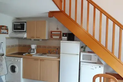 a kitchen with a white refrigerator and a staircase at Maison de vacances climatisée 600m de la mer Cour privative et parking in Port-la-Nouvelle