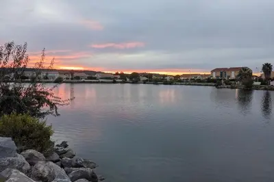 a large body of water with a sunset in the background at Maison de vacances climatisée 600m de la mer Cour privative et parking in Port-la-Nouvelle