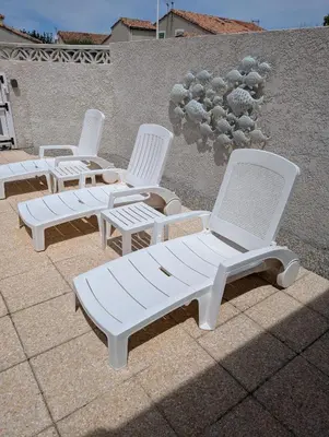 a group of white chairs sitting on a patio at Maison de vacances climatisée 600m de la mer Cour privative et parking in Port-la-Nouvelle