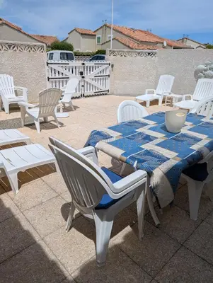 a table with a blue and white table cloth and chairs at Maison de vacances climatisée 600m de la mer Cour privative et parking in Port-la-Nouvelle