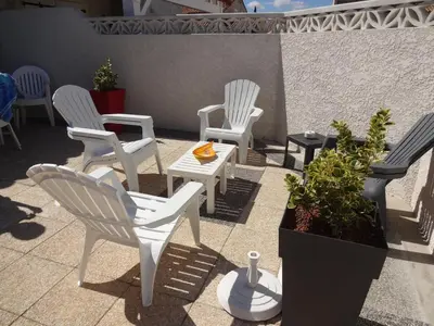 a group of white chairs and a table on a patio at Maison de vacances climatisée 600m de la mer Cour privative et parking in Port-la-Nouvelle