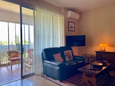 a living room with a blue chair and a balcony at Le Vintage des Oliviers - Vue Aude ascenseur et parking in Carcassonne