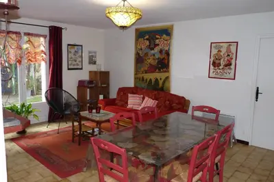 a living room with a glass table and red chairs at Villa hameau paisible Ardouane, à côté voie verte in Riols