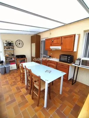 a kitchen with a white table and wooden cabinets at Lumineuse villa au pied de la pinède in Lézignan-Corbières