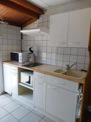 a kitchen with white cabinets and a sink and a microwave at La Maison de la Plage in Port-la-Nouvelle