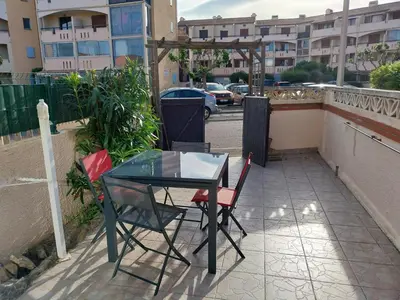 a table and chairs on a patio with a street at La Maison de la Plage in Port-la-Nouvelle
