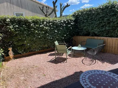 a patio with chairs and a table and a hedge at Appartement vue château in Carcassonne