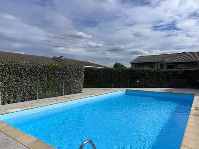 a blue swimming pool in front of a fence at Appartement vue château in Carcassonne
