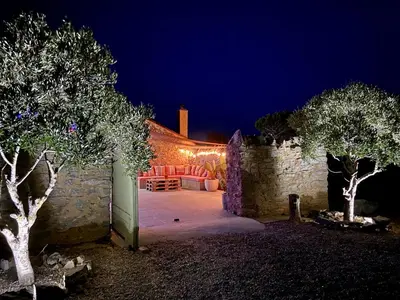 a patio at night with a stone wall at Bergerie bonheur! in Port-la-Nouvelle