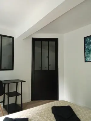 a bedroom with a black door and a table at La Céliane- climatisé avec patio classé 3 étoiles in Castelnaudary