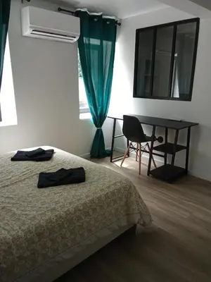 a bedroom with a bed and a desk and a window at La Céliane- climatisé avec patio classé 3 étoiles in Castelnaudary