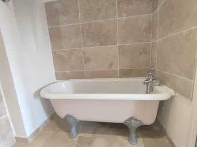 a white bath tub in a bathroom with a tile wall at La Redorte Appartement au château 8 in La Redorte